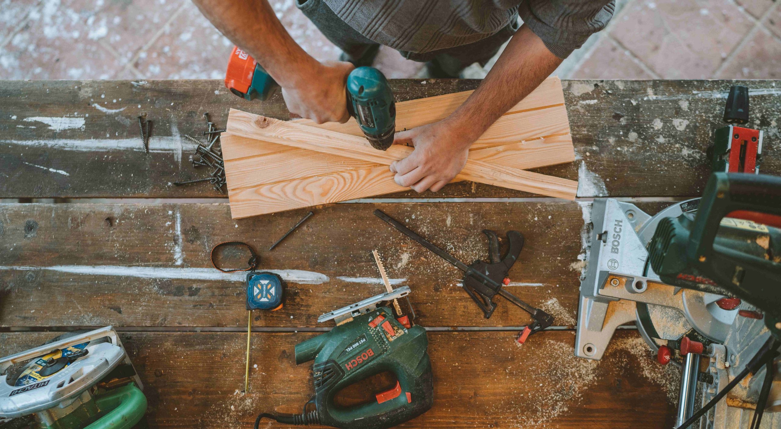 Overhead View of a Handyman Drilling Into a Piece of Wood at a Workstation