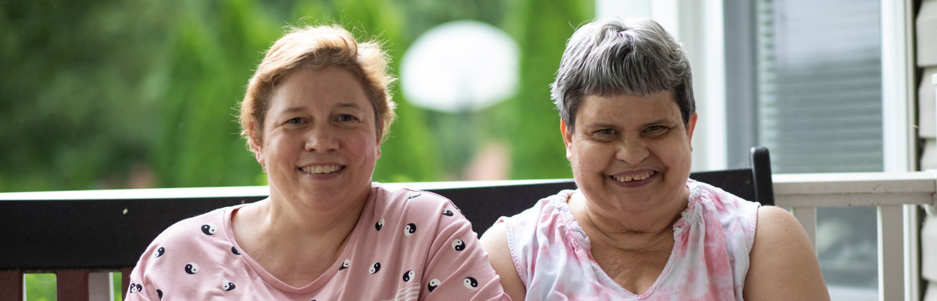 Two women sitting outside smiling.