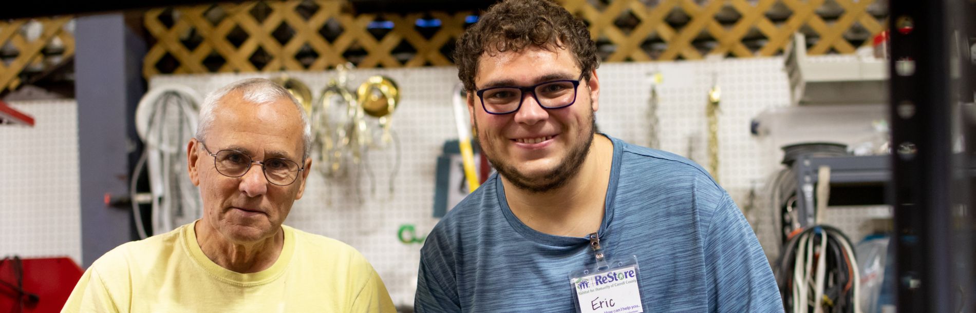 2 men smiling in a workshop.