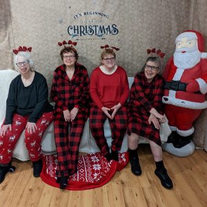 4 women sitting on a couch smiling.