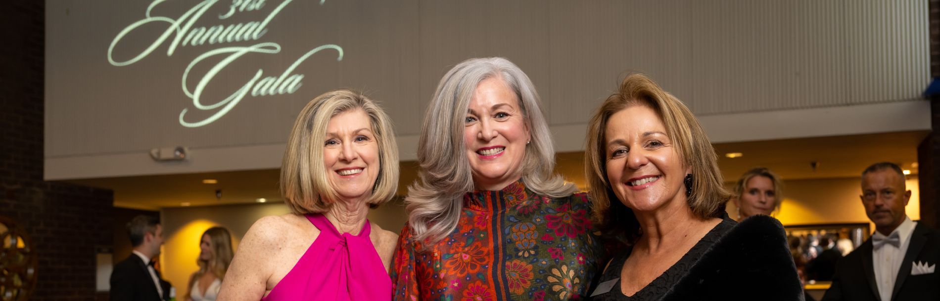 3 women smiling at a gala event.