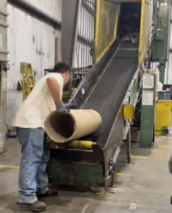 A man at work loading a tube onto the conveyor belt.