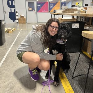 Diana crouching down to hug her service dog.