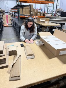 Diana at a workstation banding envelopes together.