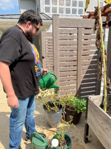 A man watering plants using a watering can.