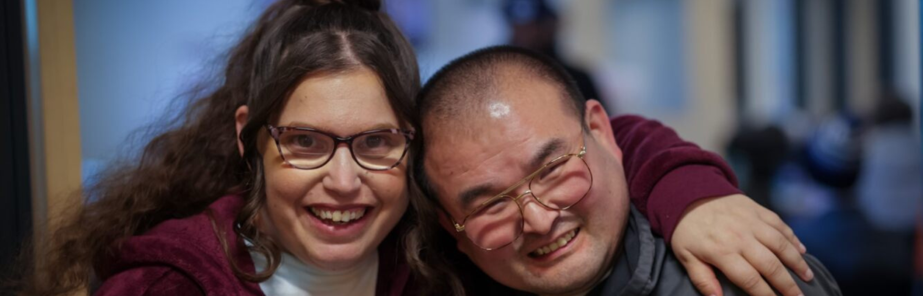 A woman on the left with her arm around a man and both are smiling.