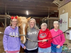 4 women standing next to a horse.