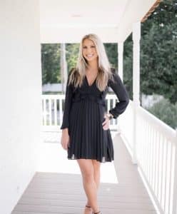 Leah standing on a porch smiling.