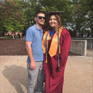 Jessica poses with her husband in her cap and gown at her graduation. 