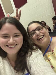 Megan smiling on the left with a woman on her right smiling with two fingers behind Megan's head.
