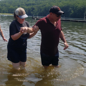 Susan Wagner helps stabilize a person she supports as they wade through a lake.