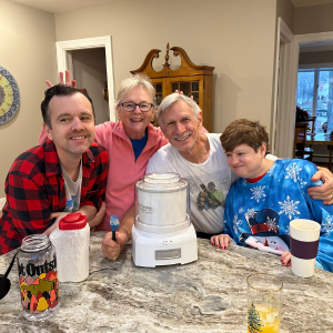 Kathleen, her husband, and her children David and Kara stand together around a kitchen counter with their arms around each other.