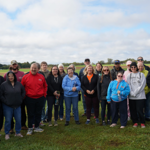 A group of people supported from Penn-Mar, DSPs, and Kelly Benefits employees pose together at First Fruits Farm.