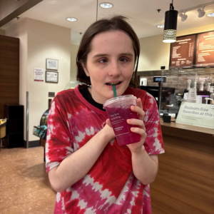 Saar smiles and drinks a beverage in a cafe.