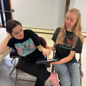 Saar uses a tablet as Corina assists her.