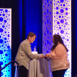 Amanda shakes a person's hand on stage as she accepts her award.