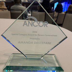Amanda's glass transparent engraved ANCOR award trophy sits on a table with a white tablecloth.