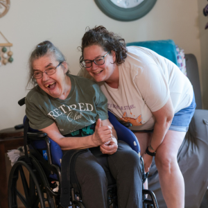 A DSP and a person supported in a wheelchair smile at the camera.