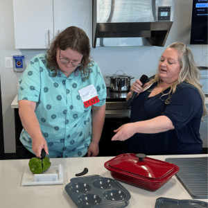 Aime Newton (left) helps coworker Allis Kensing demonstrate an Assistive Technology tool.