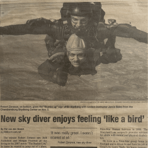 A newspaper clipping with a photo of two people skydiving with the title "New sky diver enjoys feeling 'like a bird'"