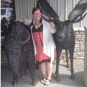 Michelle Delozier poses next to statues of moose.